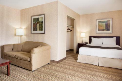 a hotel room with a bed and a chair at Days Inn by Wyndham Brantford in Brantford