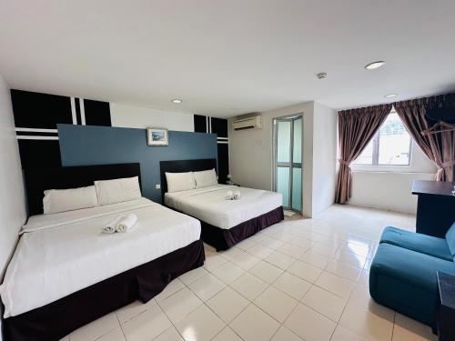 ein Hotelzimmer mit 2 Betten und einem blauen Sofa in der Unterkunft Your Hotel Klang in Klang