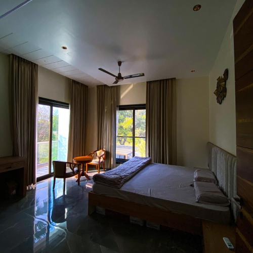 a bedroom with a bed and a desk and windows at A Creation Farm Stay in Shamshabad