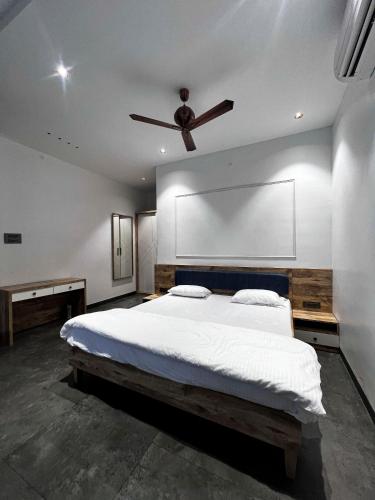 a bedroom with a large bed with a ceiling fan at A Creation Farm Stay in Shamshabad