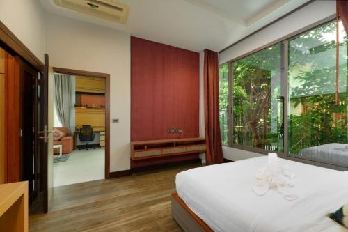 a bedroom with a white bed and a large window at Villa Pattara Rawai in Ban Saiyuan (1)