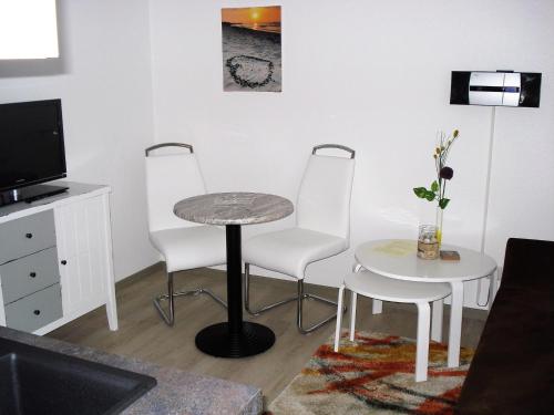 sala de estar con 2 sillas, mesa y TV en Hermer Suite 3, en Grömitz