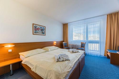 Cette chambre comprend un grand lit et un bureau. dans l'établissement Hotel RYSY, à Tatranska Strba