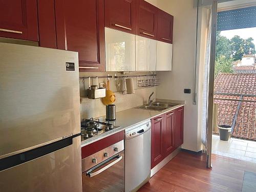 uma cozinha com armários vermelhos e um frigorífico de aço inoxidável em Fronte Mura em Lucca