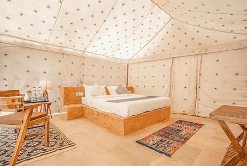 1 dormitorio con 1 cama y 1 mesa en una habitación en Jaisan Boutique Desert Camp Jaisalmer, en Jaisalmer