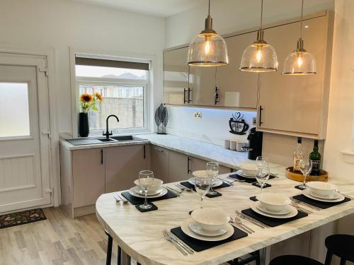 a kitchen with a table with plates and wine glasses at Harling House in Prestwick