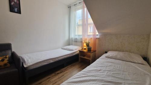 two beds in a small room with a window at Apartament w centrum Piwnicznej in Piwniczna-Zdrój