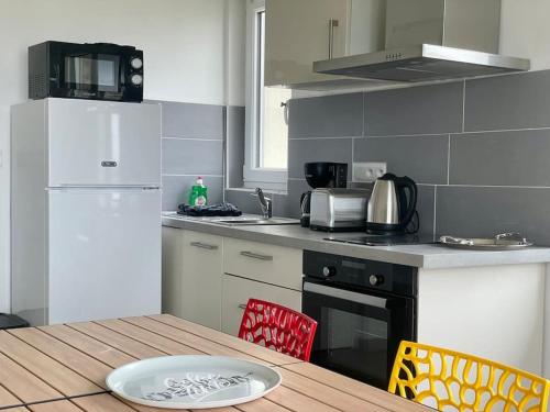 une cuisine avec une table et un réfrigérateur blanc dans l'établissement Bellavista #6 by Melrose, à Arromanches-les-Bains