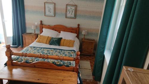 een slaapkamer met een houten bed met kussens bij Le Black Dog Pub in Saint-Aignan