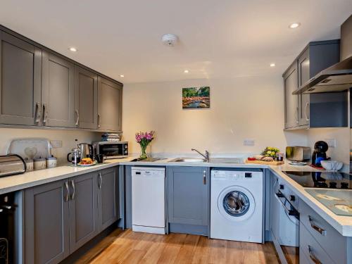 cocina con armarios grises, lavadora y secadora en 2 bed property in Chulmleigh Devon 75273, en Chulmleigh