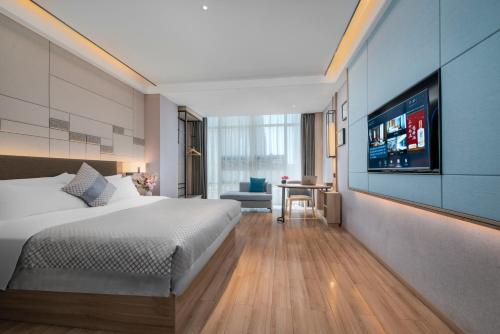ein Schlafzimmer mit einem Bett und einem TV an der Wand in der Unterkunft Morning Hotel, Poyang Sports Center in Boyang