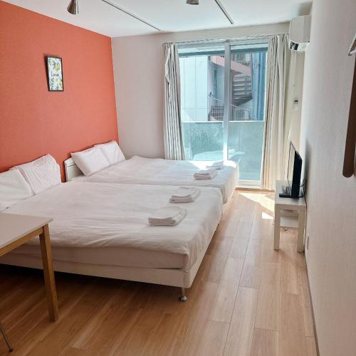 - une chambre avec 2 lits, une télévision et une fenêtre dans l'établissement 難波民泊501, à Osaka