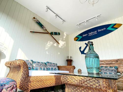 a living room with a couch and a surfboard on the wall at Baan Sailboat Beach Kohlarn in Ko Larn