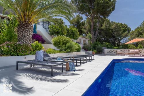 a swimming pool with chaise lounges next to a resort at Villa Corasol by Abahana Villas in Teulada