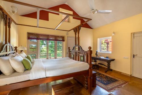 マハバレシュワールにあるSaffronStays Garnet Houseのベッドルーム(天蓋付きベッド1台、デスク付)