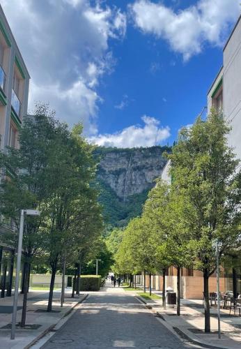 a street with trees and a mountain in the background at Appartamento vista Muse con parcheggio privato gratuito in Trento