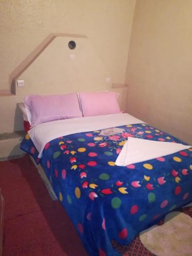 a bed with a colorful comforter in a room at Riad Bouchra in Tamtetoucht
