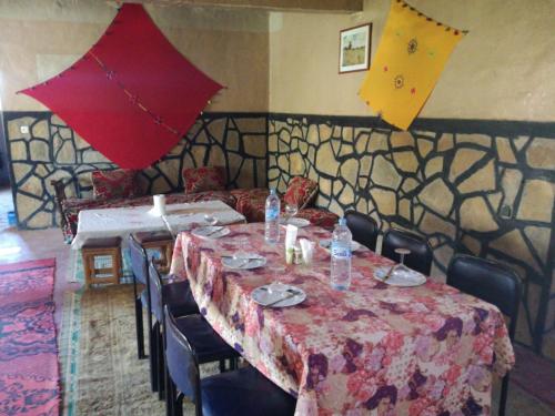 a dining room with a table and chairs and umbrellas at Riad Bouchra in Tamtetoucht