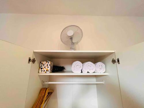 a white shelf with a fan and some towels at St Pancras Private Rooms in London