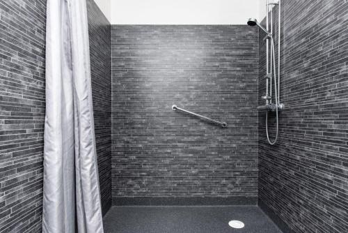 La salle de bains est pourvue d'une douche et d'un mur en briques. dans l'établissement Varamon Vandrarhem, à Motala