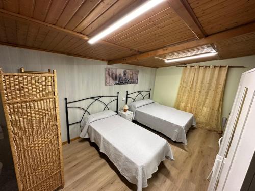 1 dormitorio con 2 camas y suelo de madera en Rural El Bosque en Entrambasaguas