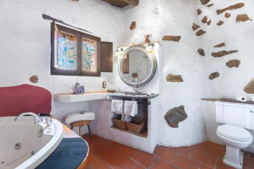 bagno con lavandino, servizi igienici e specchio di El Cau a La Torre d'En Besora