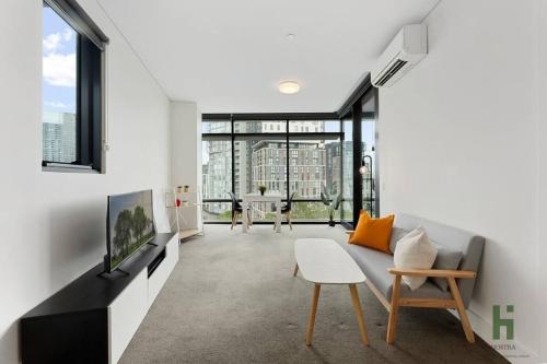 a living room with a couch and a tv at Cozy 1 bedroom at Olympic Park with one carspace in Sydney