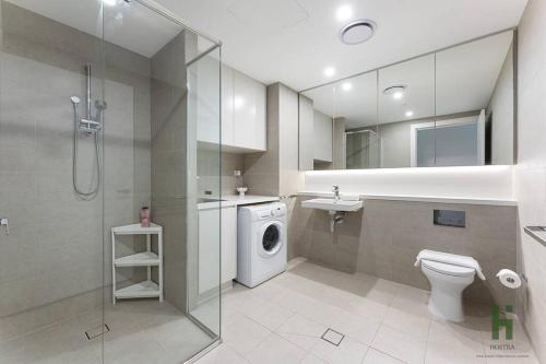 a bathroom with a toilet sink and a washing machine at Cozy 1 bedroom at Olympic Park with one carspace in Sydney
