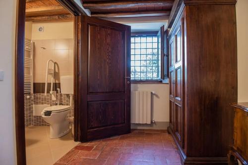 ein Badezimmer mit einem WC und einer Holztür in der Unterkunft Tabor~ Foresteria San Leolino a Panzano in Pieve di Panzano
