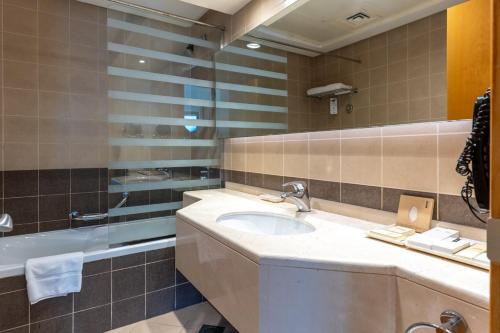 a bathroom with a sink and a tub at Grand Bellevue Hotel Apartment Dubai in Dubai