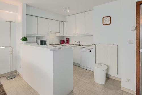 uma cozinha branca com armários brancos e um balcão em Stephanie 0401 G em Sint-Idesbald