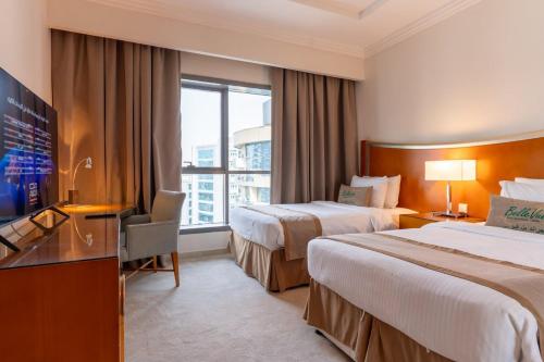 a hotel room with two beds and a television at Grand Bellevue Hotel Apartment Dubai in Dubai