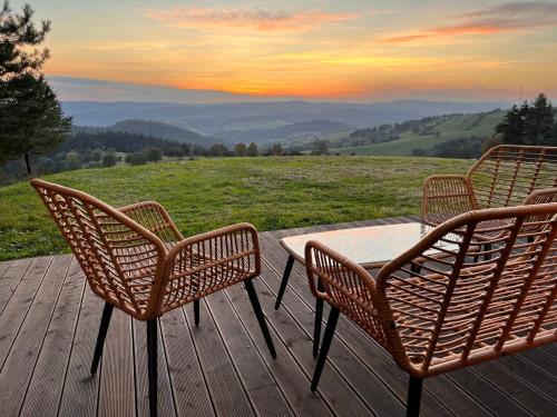 three chairs and a table on a deck with a view at Chaty w chmurach in Komańcza