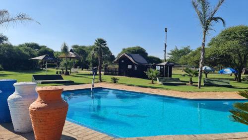 a swimming pool with two large vases next to it at Luxury Tents Belabela Resort Warmbath in Bela-Bela