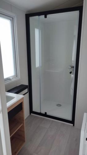 a bathroom with a glass shower with a sink at Tiny house camping Ambon in Ambon