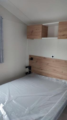 a bedroom with a white bed with a wooden headboard at Tiny house camping Ambon in Ambon