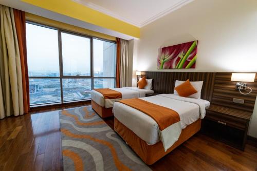 a hotel room with two beds and a large window at Abidos Hotel Apartment Dubai Land in Dubai