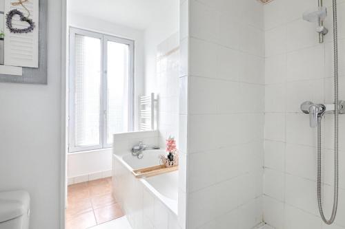 La salle de bains blanche est pourvue d'une douche et de toilettes. dans l'établissement La Vie en Rose - Paris - A 5 min de Paris, à Saint-Maurice