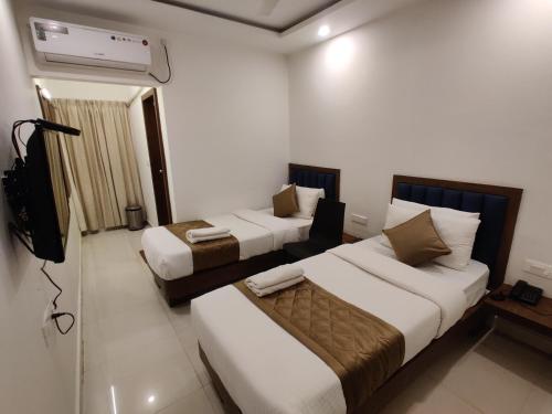 Cette chambre comprend deux lits et une télévision. dans l'établissement Airport Regency, à Devanhalli