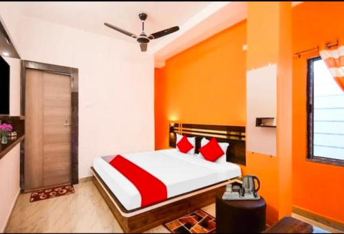 um quarto com paredes laranja e uma cama com almofadas vermelhas em Oyo chinar haven em Salua