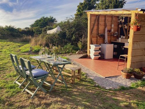 a table and chairs in a garden with a kitchen at Foxglove Field Glamping in Perranuthnoe