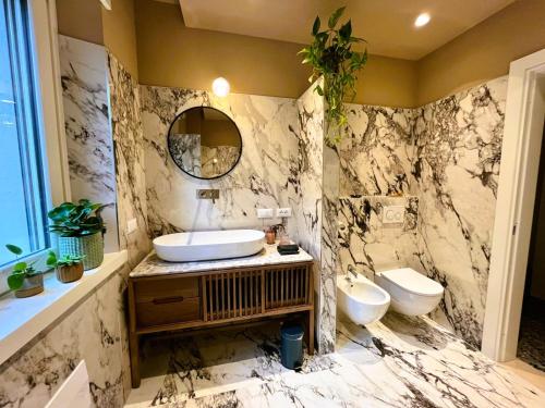 a marble bathroom with a sink and a toilet at Villa Lou in Toscolano Maderno