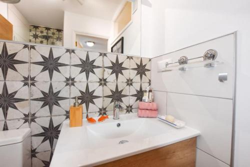 een badkamer met een wastafel en een betegelde muur bij Book Jet - Casa Adam BEACH & WIFI in Morro del Jable