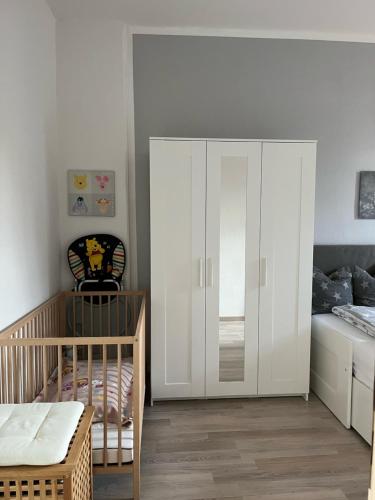 um quarto para bebés com um berço e um armário branco em Gästewohnung zum Heiligen Grund em Meissen