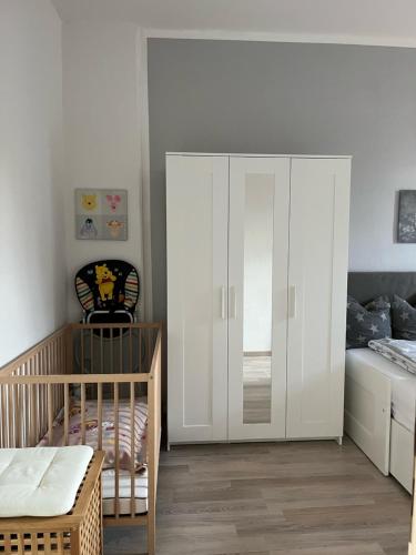 a baby room with a crib and a white cabinet at Gästewohnung zum Heiligen Grund in Meißen