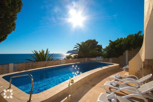 una piscina con sillas y el océano en el fondo en Villa Dauphin by Abahana Villas, en Moraira