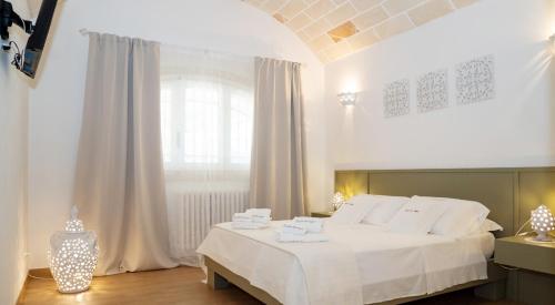 a bedroom with a white bed and a window at Trullo dei Sogni con Piscina e Jacuzzi in San Michele Salentino
