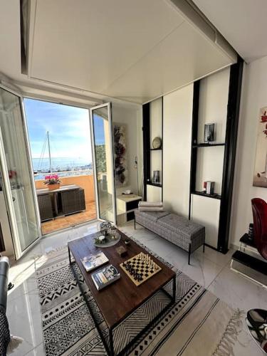 un salon avec une table et une grande fenêtre dans l'établissement Studio VUE MER IMPRENABLE PLEIN SUD à GOLFE JUAN, à Vallauris