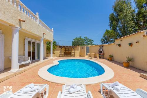 una piscina en medio de un patio con sillas blancas en Villa Delicia by Abahana Villas, en Calpe