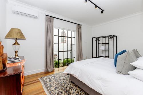 a bedroom with a bed and a desk and a window at La Maison On Main Self-Catering Villa in Paarl